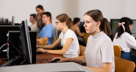 Smart female teenager learning computer science while she is using a PC in the computer classroom