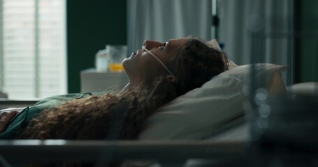 Young girl opens her eyes and gazes upward after a nap in her hospital bed.