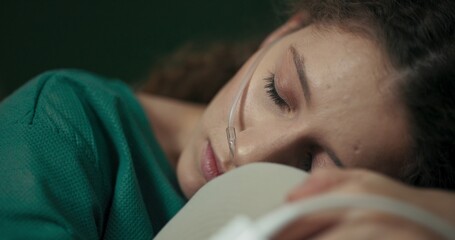 Sitting on her hospital bed, the young girl wraps her arms around her knees, seeking solace.
