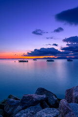 Serene Sunset Over Lake  Garda with Boats and Rocky Shore