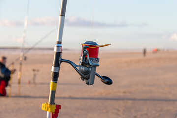 man fishing on beach, close up of fishing rod and reel