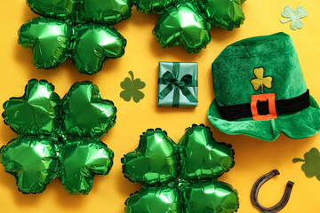 Balloons in shape of clover, leprechaun's hat, gift box and horseshoe on yellow background. St....