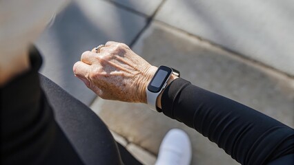 A closeup of an elderly womans arm clad in a fitness tracker displaying her active lifestyle as she monitors her daily steps while walking outdoors.