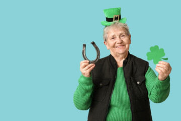 Senior woman in leprechaun hat with horseshoe and clover on blue background. St. Patrick's Day...