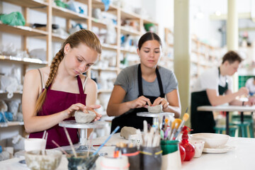 Teenagers are interested in making dishes from clay in a pottery workshop