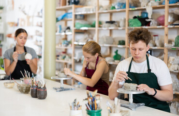 Teenage boy and teenage girl students in apron make clay product in ceramic workshop