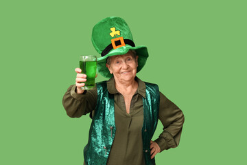 Senior woman in leprechaun hat with glass of beer on green background. St. Patrick's Day celebration