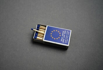 Matchbox European flag. Wooden matches row. Gray textured surface. Symbolic packaging view.


