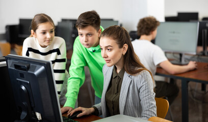 Teacher helping young student in computer class in university