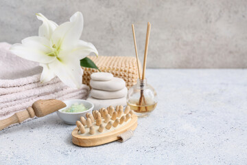 Composition with body massage brush, sea salt, lily flower and scoop on grunge background, closeup