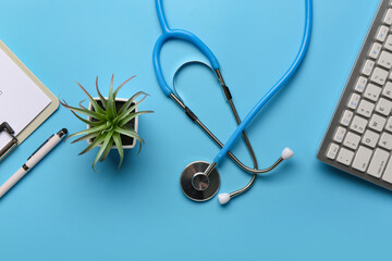 Modern computer keyboard, houseplant, clipboard and stethoscope on blue background