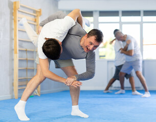 Young guy and man practice wrestling, apply techniques of Aikido and self-defense. Training battle...