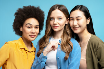 Portrait of group diverse multinational women smiling and posing together on blue background