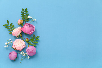 Beautiful composition with different flowers and green leaves on blue background