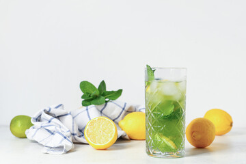 Glass of lemonade with lemons and mint on white background