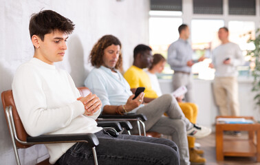Portrait of a young man sitting in a chair in the lobby waiting