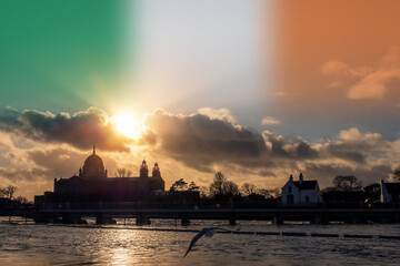 Silhouette of Galway Cathedral building and river Corrib. Dramatic sky with sun and Irish flag. City landmark. Galway city, Ireland. Travel and tourism