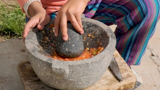  latina girl's hands grinding in mortar or also called batan in the backyard of her house in la paz, bolivia - cooking concept