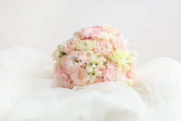 Beautiful wedding bouquet and bride's veil on light background