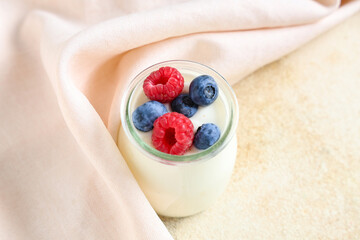 Jar of tasty yogurt with fresh blueberries and raspberries on white background