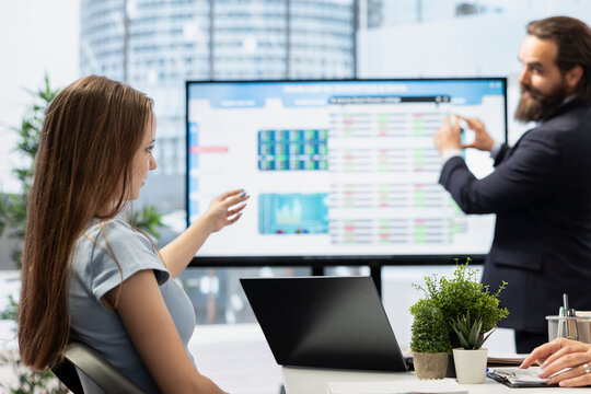 Financial advisor using presentation on big screen to help teenager manage diversified investment portfolios. Agent uses large display to provide gen Z girl mix of stocks, bonds and other assets
