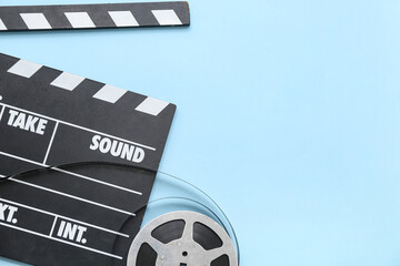 Movie clapper with film reel on blue background