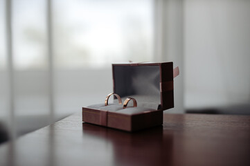 Close-up of two wedding rings placed inside a soft, elegant gift box on a wooden table with a soft background.
