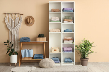 Stylish interior of modern dressing room with folded clothes and houseplants