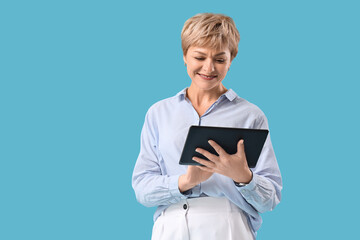Mature businesswoman using tablet computer on blue background