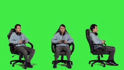 Obraz premium Woman gamer playing online video games with controller, sitting in an office chair against greenscreen backdrop. Joyful person having fun with e sport competition, modern gaming setup. Camera A.