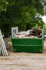 Industrial waste container filled with construction waste, located in the block's yard. Vertical...