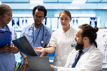 Diverse team of healthcare providers reviewing test lab results in a clinical setting, focusing on...