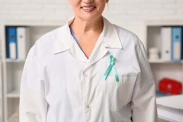 Mature female doctor with teal ribbon in clinic. Cervical Health Awareness Month