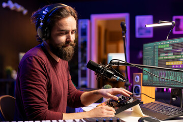 Young composer musician singing lyrics on microphone in his home studio, operating on stereo...