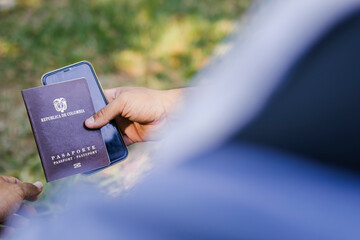 Young latino backpacker showing colombian passport and smartphone