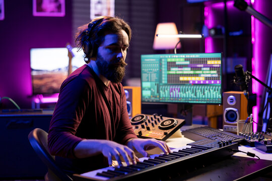 Skilled musician artist playing piano synthesizer notes for audio recording session, working in musical post production. Talented singer editing songs and adding sound effects in home studio.