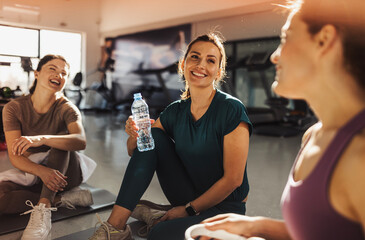 Women resting and enjoying post-workout conversation at the gym