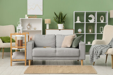Cozy sofa, armchair and shelving unit in interior of living room
