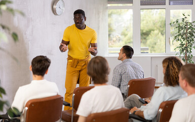 Fototapeta premium African american man leads a lecture in the audience during a group meeting of men gays