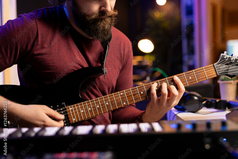 Poster musical artist playing acoustic guitar and recording a new song in home studio, using modern acousti