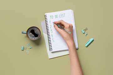 Female hand with to do list, cup of coffee and stationery on green background. Top view