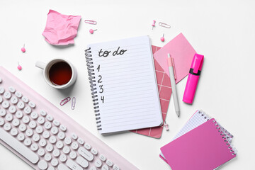 Notebook with blank to do list, cup of tea, stationery and keyboard on white background. Top view
