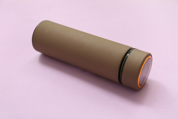 Brown modern thermos on lilac background