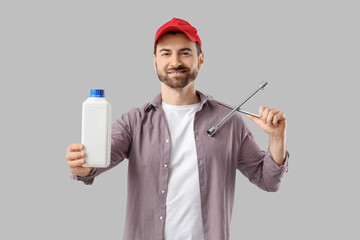 Young man with canister and cross wrench on grey background
