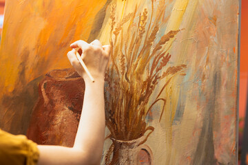 Artisan inspired by natural rural elements to paint a masterpiece on canvas, using modern paintbrushes in art studio. Working with motivation and creativity for fine art creative process. Close up.