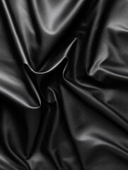 Fototapeta premium Close-up view of smooth black leather fabric showing intricate folds and texture in a soft light