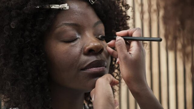 Makeup artist applying eyeshadow on a black african woman