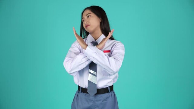 Indonesian female high shool student in uniform showing cross sign saying no