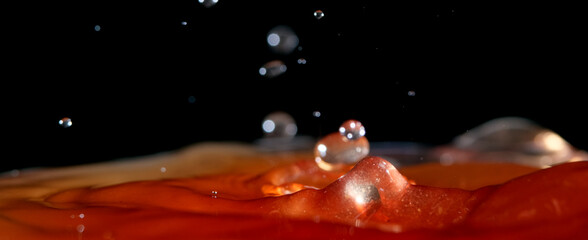 Macro shot splash of apple cider vinegar on black background