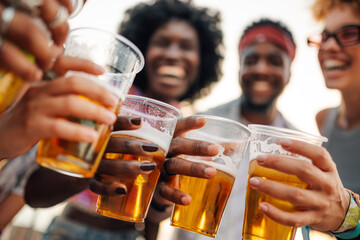 Happy friends toasting with beer at music festival